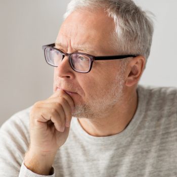 old age, problem and people concept - close up of senior man in glasses thinking